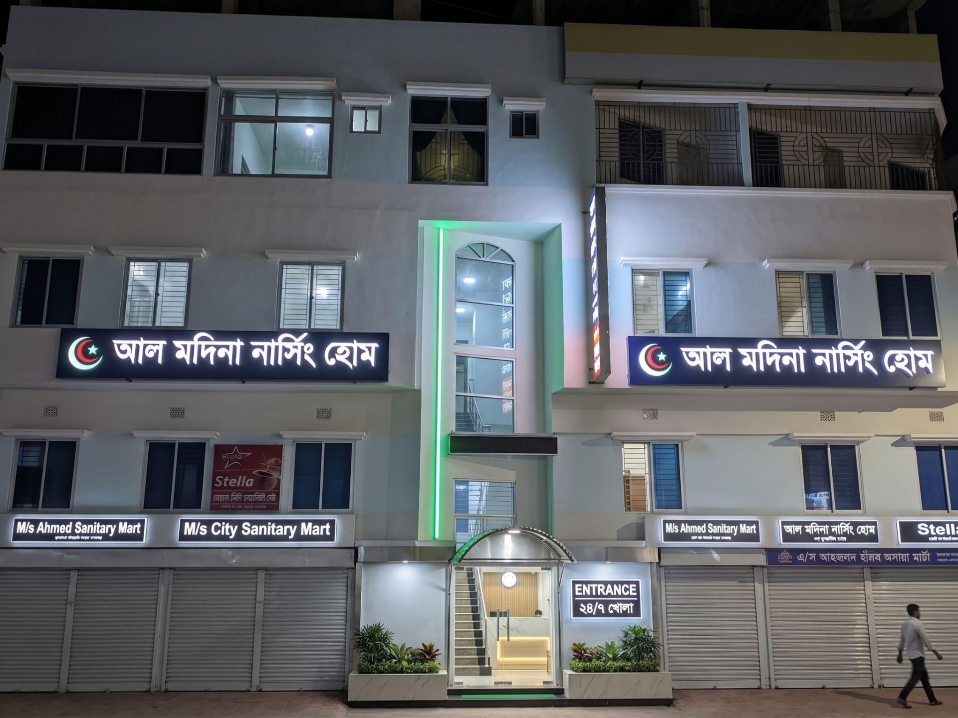 Illuminated exterior of the Al-Madina Nursing Home & Diagnostic Centre building at night with signage